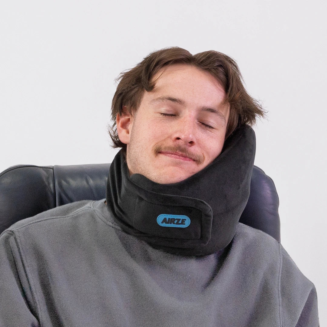 Traveler resting comfortably with the Airze travel pillow in black, designed for neck support and relaxation during travel.
