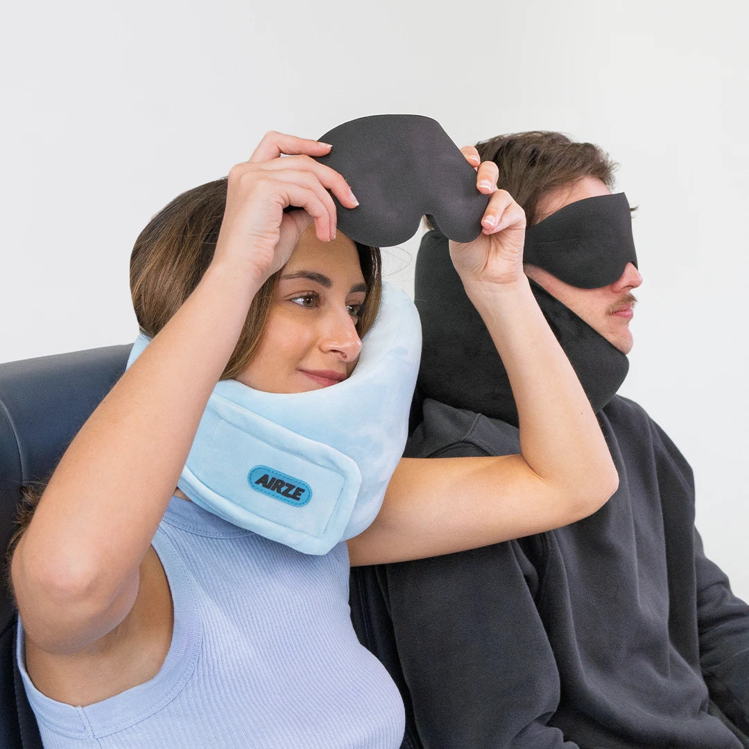 Travelers using the Airze Eze Sleep Bundle, mid-action while putting on the contoured sleep mask, demonstrating ease of use for ultimate travel comfort.