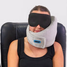 Traveler using the Airze Eze Sleep Bundle with a grey travel pillow and blackout sleep mask, providing neck support and ultimate travel comfort.