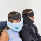 Two travelers using the Airze Eze Sleep Bundle, featuring a supportive travel pillow and blackout sleeping mask for ultimate travel comfort.