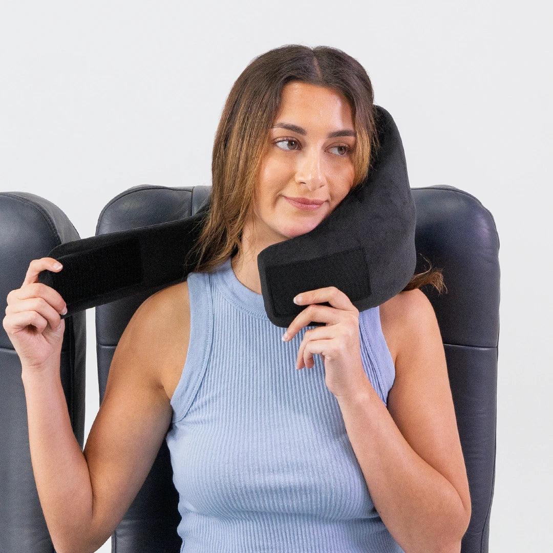 Traveler demonstrating how easy it is to put on the Airze travel pillow in black, showcasing its adjustable fit and ergonomic neck support for superior travel comfort.