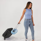 Traveler carrying the Airze travel pillow in blue, securely attached to a suitcase handle for hands-free travel convenience.