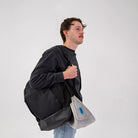 Traveler carrying the Airze travel pillow in grey, conveniently attached to a backpack for easy portability and hands-free travel comfort.